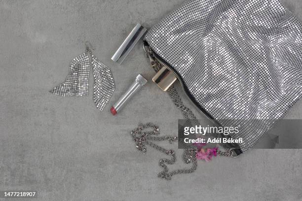 top view of silver colored sequin makeup bag with beauty items around - silver purse stock-fotos und bilder