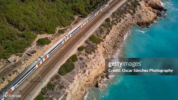 aerial view of the train tracks passing near the coastline along the mediterranean sea - aerial train stock-fotos und bilder