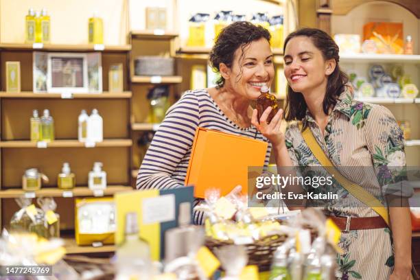 mother and her adult daughter are shopping together - choosing perfume stock pictures, royalty-free photos & images