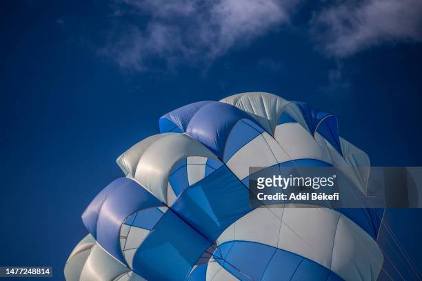 low angle view of blue and white parachute against sky - fallschirmsprung stock-fotos und bilder
