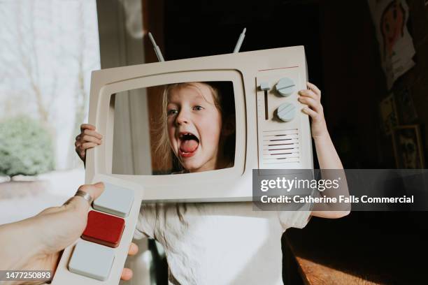 conceptual image of a noisy child pretending to be on television using a wooden toy prop - girls television show fotografías e imágenes de stock