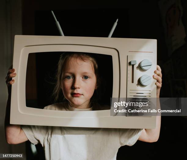 a little girl looks out from behind a toy television - reality tv stock pictures, royalty-free photos & images