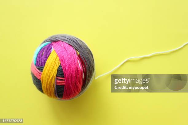 overhead view of a ball of multi coloured yarn scraps on a yellow background - ball of wool ストックフォトと画像