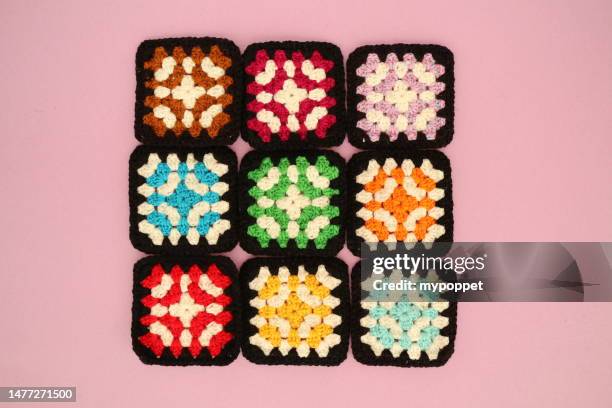 close-up overhead view of nine crochet squares on a pink background - crochet stock-fotos und bilder