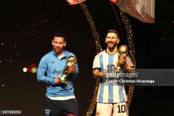 Lionel Messi of Argentina poses with the FIFA World Cup trophy next to a statue of himself during an event organized by CONMEBOL at their...