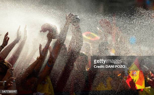 Fans celebrate as the Spanish national football team arrives on Cibeles Square on July 2, 2012 after parading through Madrid, a day after it won the...