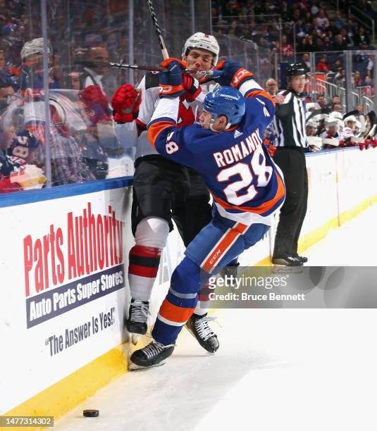 John Marino of the New Jersey Devils is checked by Alexander Romanov of the New York Islanders during the third period at the UBS Arena on March 27,...