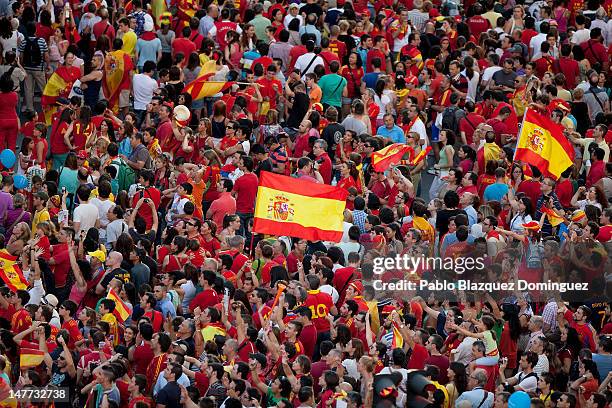 Spain fans fly the national flag as crowds of wait to celebrate with the players as they parade the UEFA EURO 2012 trophy on a double-decker bus on...