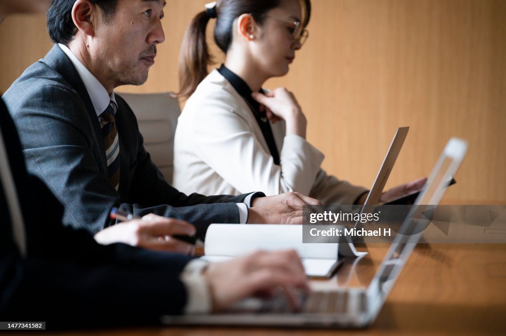 People are sitting side by side in a conference room.
Close-up of hands typing on laptops
