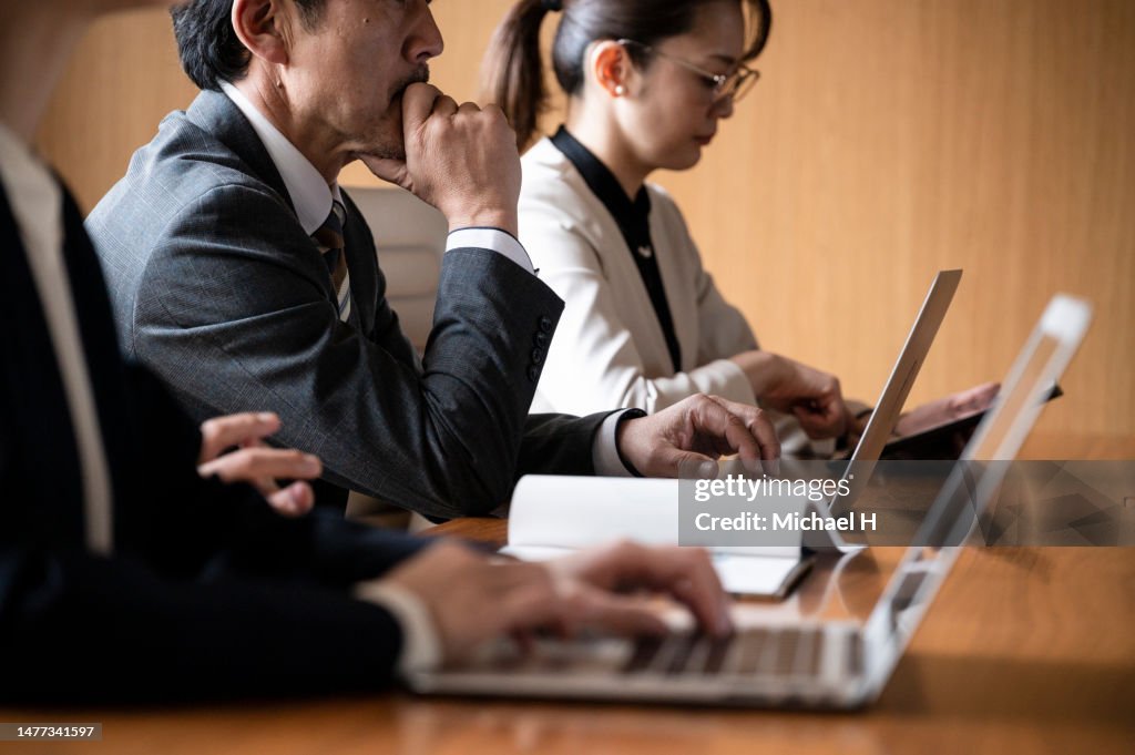 People are sitting side by side in a conference room.
Close-up of hands typing on laptops