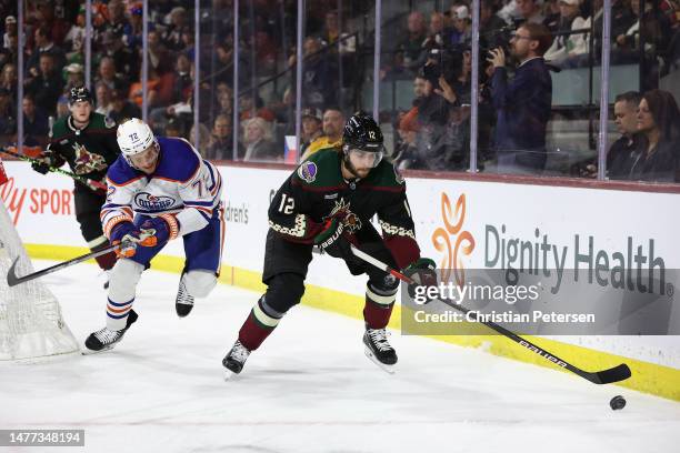 Connor Mackey of the Arizona Coyotes skates with the puck ahead of Nick Bjugstad of the Edmonton Oilers during the second period of the NHL game at...