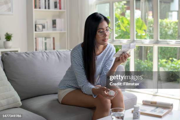 woman reading medical instructions before taking medicine. - antibiotics stock pictures, royalty-free photos & images