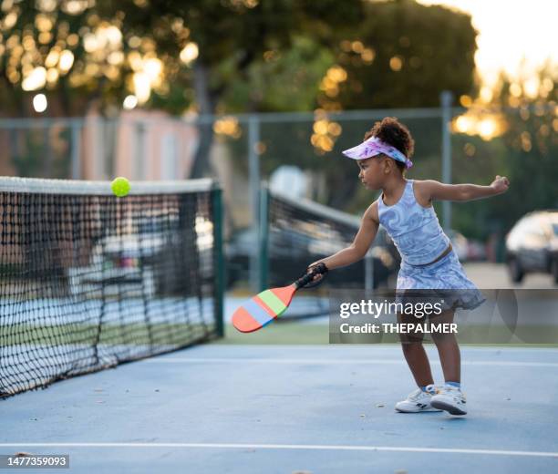 kleines mädchen, das pickleball spielt und einen aufschlag zurückgibt - sports activity stock-fotos und bilder