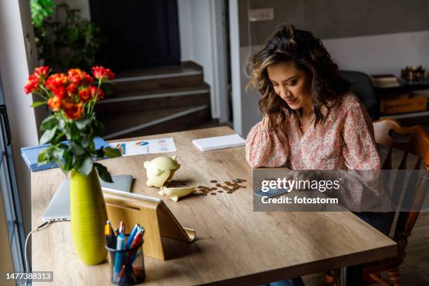 young woman counting coins from a broken piggy bank when sorting out her savings - broken calculator stock pictures, royalty-free photos & images