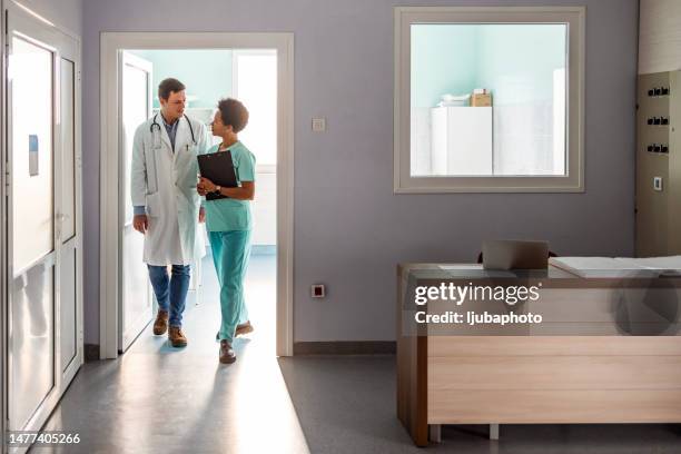 doctor and nurse walking in hospital hallway - surgeon walking stock pictures, royalty-free photos & images