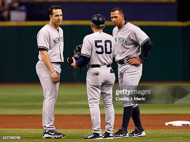 First base coach Mick Kelleher of the New York Yankees talks with Mark Teixeira and Alex Rodriguez after an inning ending double play against the...