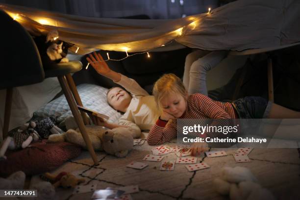 a brother and a sister playing with their cat in a homemade illuminated hut, at home - children only stock pictures, royalty-free photos & images