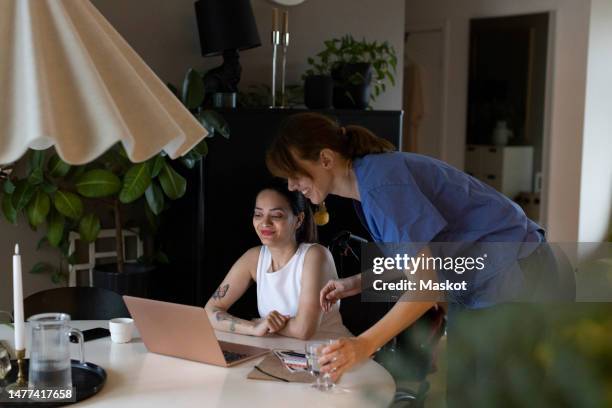 female caregiver talking to woman with paraplegia watching laptop at home - dining table icon stock pictures, royalty-free photos & images