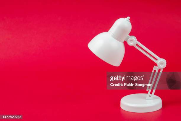 white desk lamp with copy space against a red background. minimal concept idea creative. - angle poise lamp foto e immagini stock