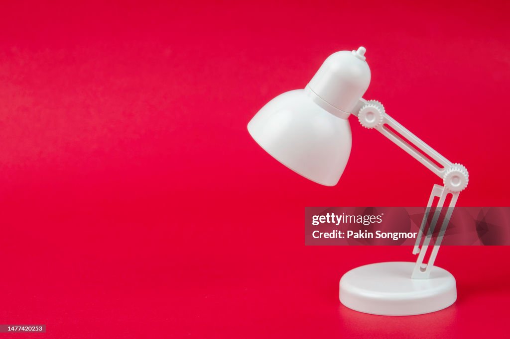 White desk lamp with copy space against a red background. minimal concept idea creative.