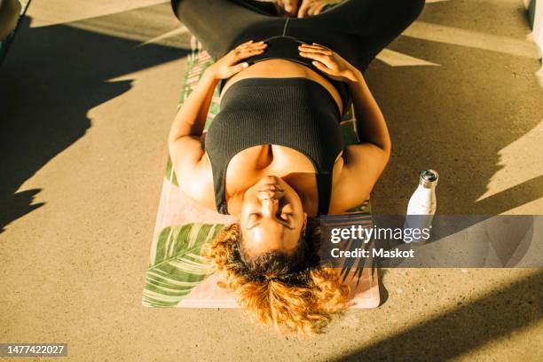 high angle view of woman exercising while lying on floor during yoga class - hands on tummy stock pictures, royalty-free photos & images