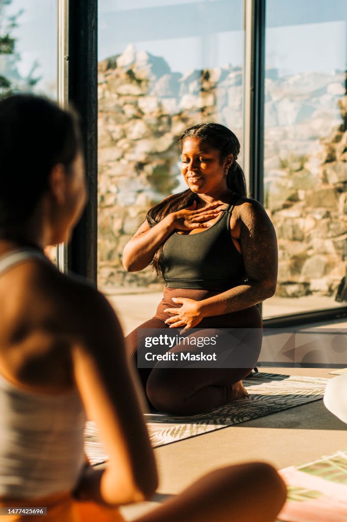 Smiling woman practicing breathing exercise in yoga class at retreat center