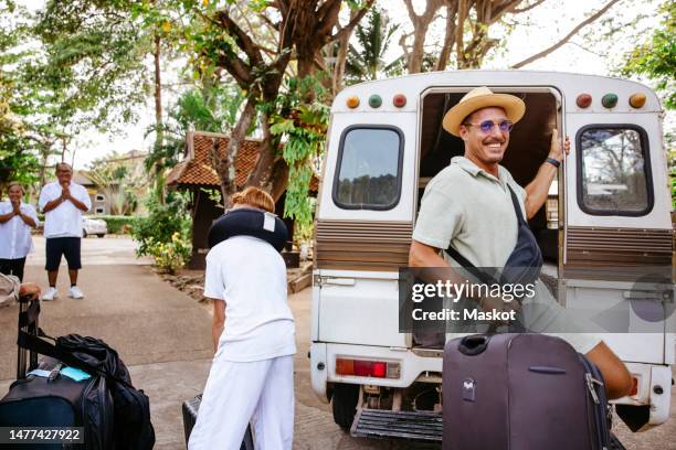 smiling male tourist getting down with luggage from van at resort during vacation - waist pack stock pictures, royalty-free photos & images