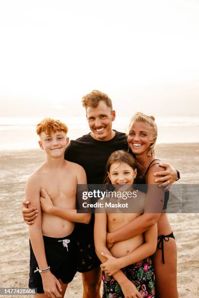 portrait of smiling family standing at beach during sunset - young teen bathing suit stock pictures, royalty-free photos & images