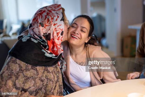 mature woman kissing daughter with paraplegia sitting at home - paraplegic stock pictures, royalty-free photos & images