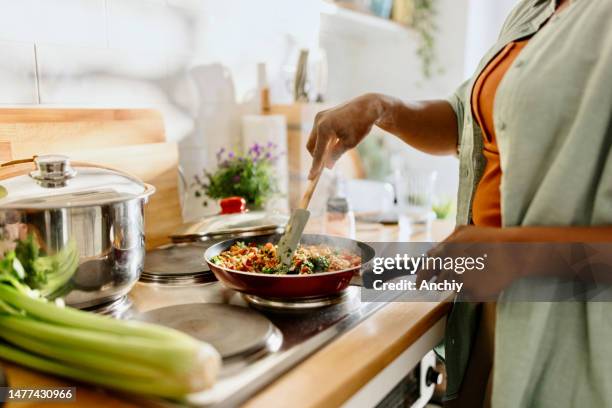 mujer preparando mezcla de verduras de quinua cocinada en una sartén - mujer cocinando fotografías e imágenes de stock