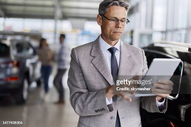 car salesperson working on digital tablet in a showroom. - touchpad bildbanksfoton och bilder