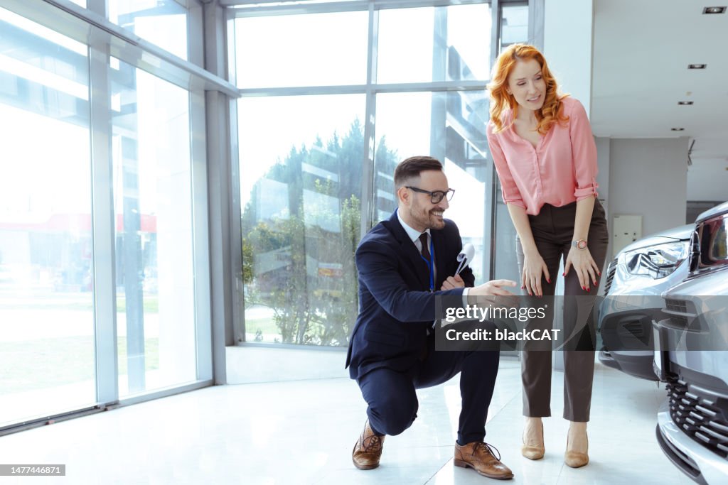 Professional salesperson selling car at dealership to buyer