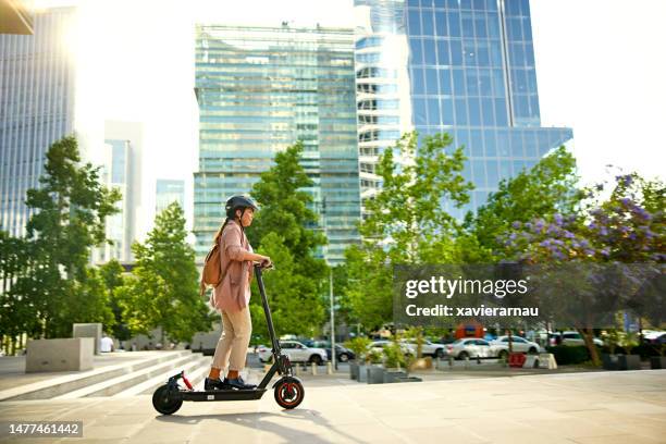 late 30s businesswoman riding electric push scooter - sustainable lifestyle stock pictures, royalty-free photos & images