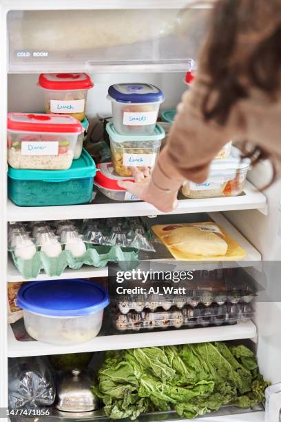 woman looking at healthy prepared meals in her fridge at home - fridge full of food stockfoto's en -beelden