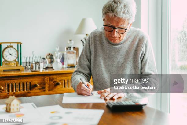 senior man signing a house sale agreement - mortgage stock pictures, royalty-free photos & images