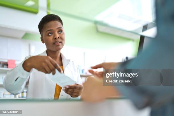 female pharmacist talking with customer - apotheker stockfoto's en -beelden