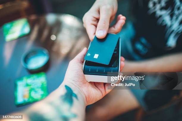 adult man paying with credit card at cafe, close-up of hands with credit card and credit card reader - holding card stock pictures, royalty-free photos & images