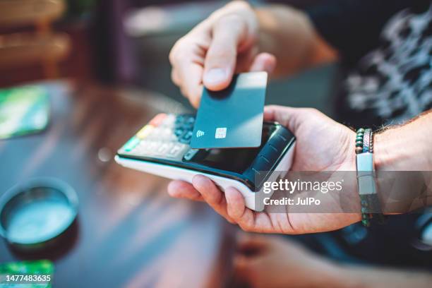 adult man paying with credit card at cafe, close-up of hands with credit card and credit card reader - paid stock pictures, royalty-free photos & images