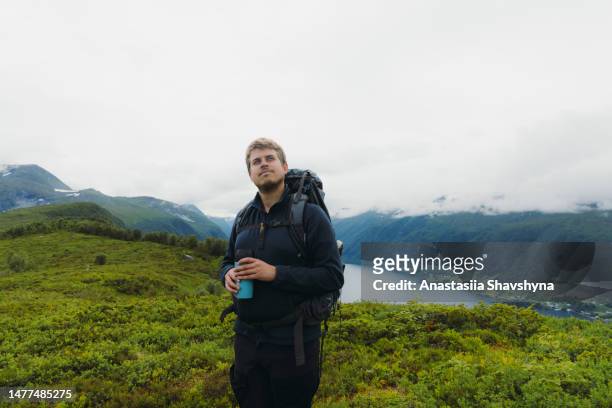 ein mann mit rucksack und thermobecher wandert in den sommerbergen norwegens - thermo becher stock-fotos und bilder