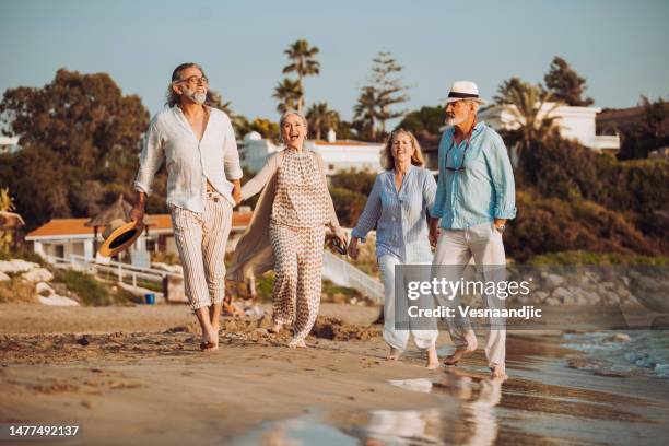 happy friends on vacation, walking by the sea - early retirement stockfoto's en -beelden