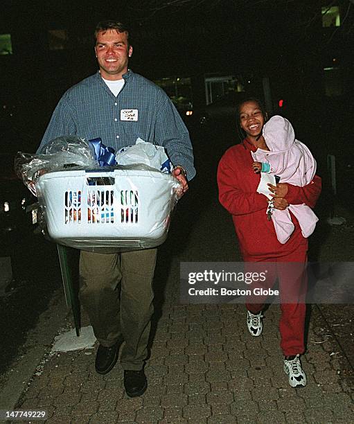 Patriots quarterback Scott Zolak helps Nicole Milton of Dorchester, who is carrying her daughter Cierra, 6 months old, out to her car with the...