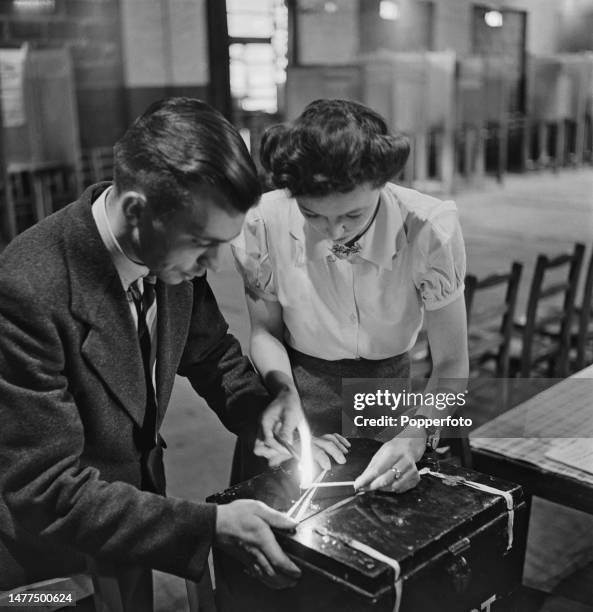 Two polling clerks use sealing wax to seal the lid of a ballot box filled with voting slips at a polling station in Camberwell, after voting in the...