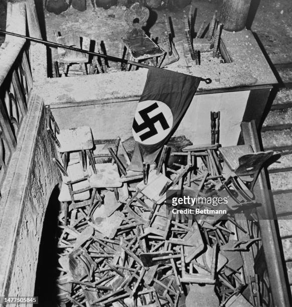Nazi flag and a pile of chairs pictured at the bomb-damaged Hofbräuhaus beer hall in Munich after soldiers of the US 7th Army took control of the...