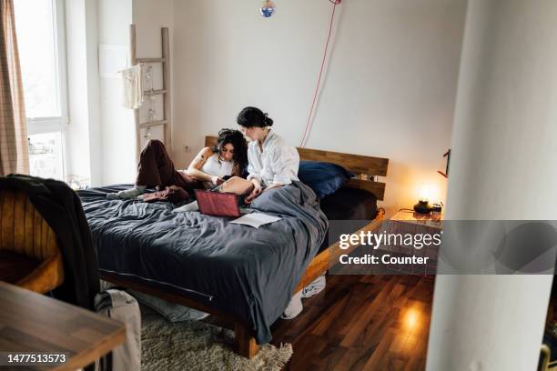 friends looking at laptop and smartphone in bed in morning - cool couple in apartment stock pictures, royalty-free photos & images