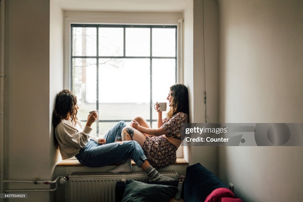Two friends drinking tea on window sill