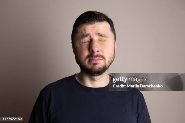 portrait of squinting bearded handsome man - pain face portrait stockfoto's en -beelden