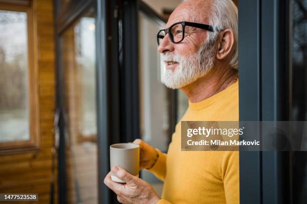 白髪の老人がコテージのテラスで朝のコーヒーを楽しむ - old man and glasses ストックフォトと画像