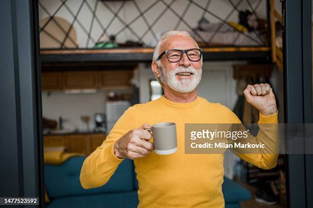 a gray-haired old man enjoys his morning coffee on the terrace of his cottage - coffee happy stock pictures, royalty-free photos & images