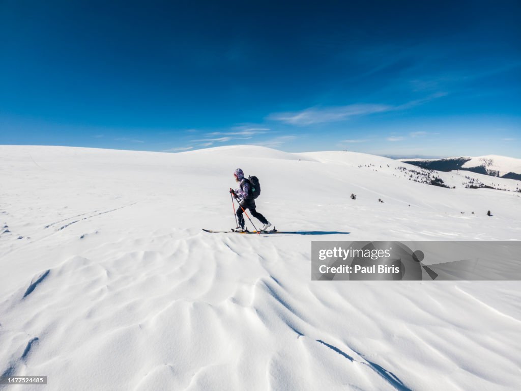 Lone female ski touring in snow covered landscape