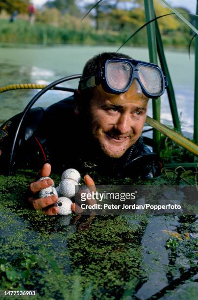 British diver Andy Taylor, wearing a wetsuit and goggles, dives for lost golf balls in ponds and water features on a golf course in southern England...